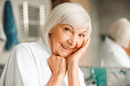 Cheerful elderly woman propping up head on handの写真素材