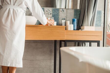 Senior lady in bathrobe holding glass of waterの写真素材