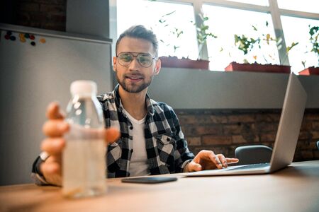 Young handsome man taking bottle of waterの写真素材