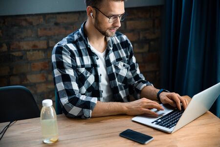 Young male typing while sitting at the table