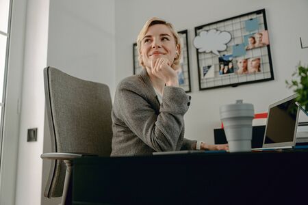 Smiling beautiful female looking away in the officeの写真素材