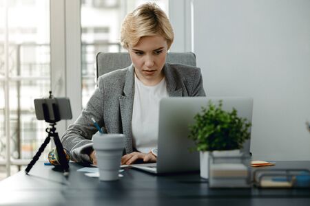 Pretty young woman taking notes at the desktop