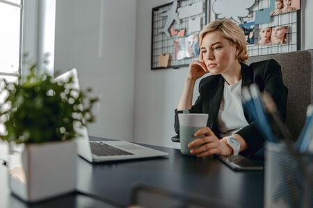 Waist up of concentrated pretty lady working while sitting in the office stock photoの写真素材