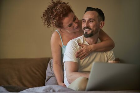Smiling pretty woman hugging man in bedroomの写真素材
