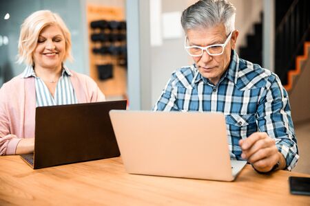 Happy pretty mature woman sitting with man at workplace