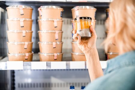 Back view of woman holding jar with dessert in supermarket stock photoの写真素材