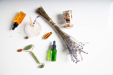 Close up of lavender bouquet, massage roller, bottles of vitamin serum and white cosmetic clay stock photoの写真素材