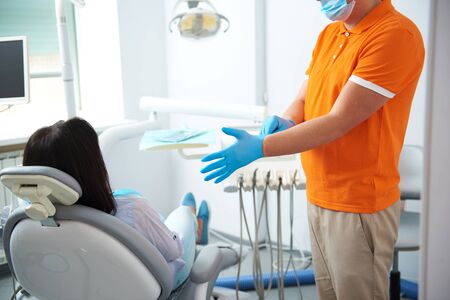 Male dentist standing near patient in roomの写真素材