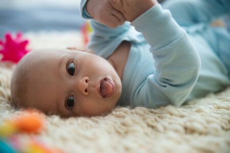Funny baby showing tongue and looking awayの写真素材