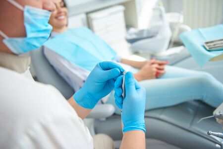 Handsome male dentist sitting near female patient