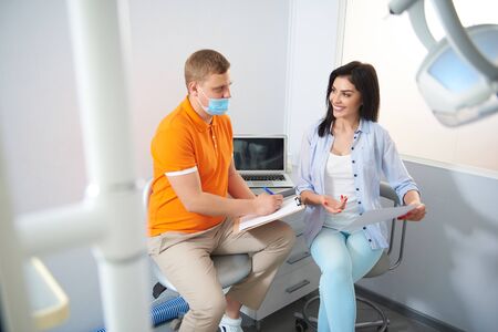 Happy lady talking with dentist in roomの写真素材