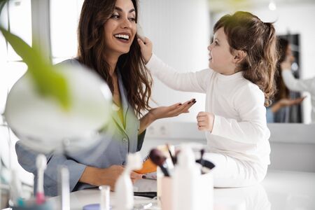 Happy pretty mom playing with her daughter in roomの写真素材