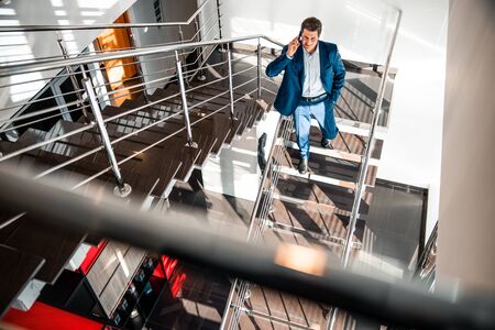 Businessman with a phone descending the staircaseの写真素材