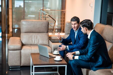 Middle-aged businessman talking to his young colleagueの写真素材