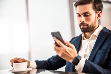 Modern office worker staring at his cellphoneの写真素材