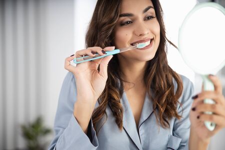 Smiling pretty lady holding mirror at homeの写真素材