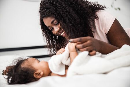 Joyful Afro American woman holding hand of baby girlの写真素材