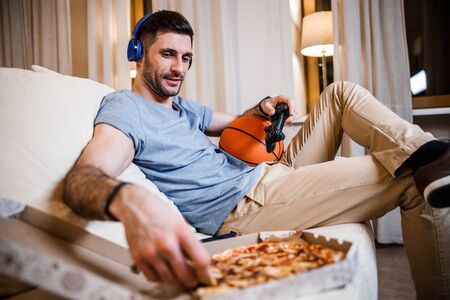 Young man with fast food and joypad stock photo
