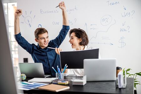 Happy man and woman celebrating success in the office