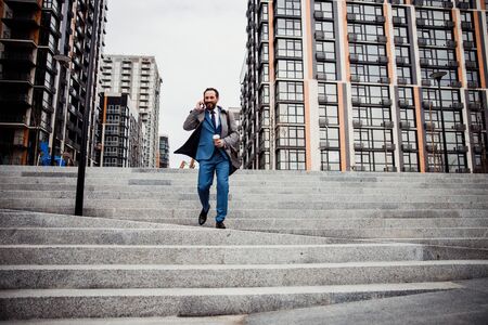 Pleased bearded man using his cellphone outdoors