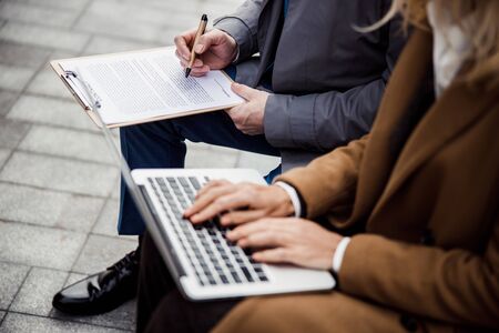 Cropped photo of a Caucasian female broker with a laptop sitting by a male buyer
