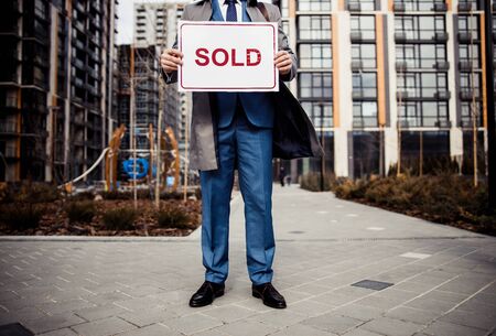 Cropped photo of a professional real estate agent holding a sold sign in his handの写真素材