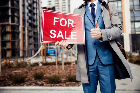 Cropped photo of a male broker with a sign in his hand advertising new apartmentsの写真素材