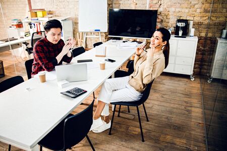 Cheerful workers sitting at office desk with laptop and coffee