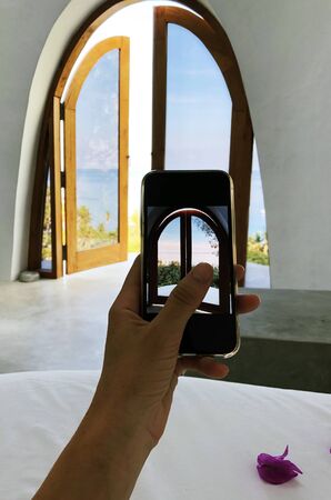 Close up of female hand holding smartphone and taking picture in hotel room stock photo