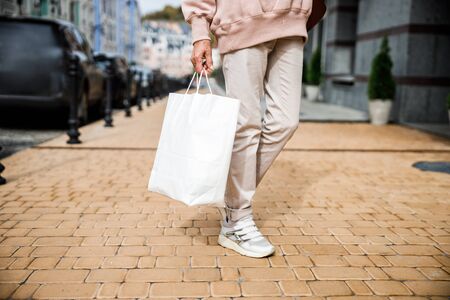 Aged female is standing in street and holding packet after shoppingの写真素材