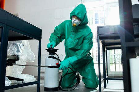 Attentive man sanitizing the floor under the table stock photoの写真素材