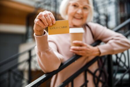 Happy elderly female with credit card outdoors stock photoの写真素材