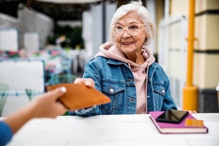 Smiling aged woman giving bill to waitress stock photoの写真素材