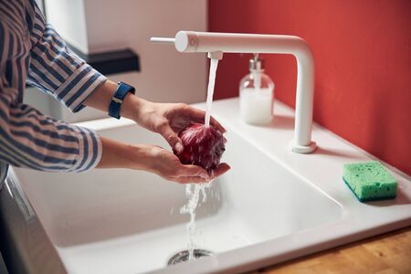 Young lady is washing apple in the sinkの写真素材