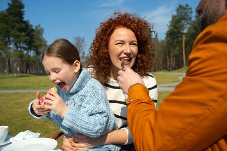 Joyful woman enjoying breakfast with husband and daughter