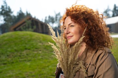 Pretty lady holding dry field grass and smilingの写真素材