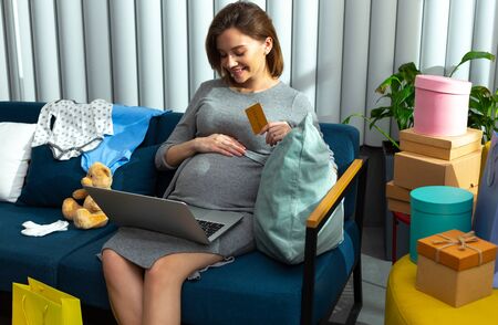 Pleased woman kindly looking at her pregnant belly and touching itの写真素材