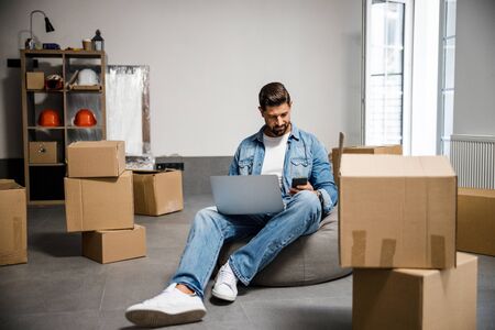 Carefree stylish male with laptop selling his apartmet