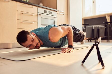 Handsome young man doing push-ups at home