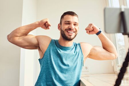Handsome young man showing biceps muscles and smilingの写真素材