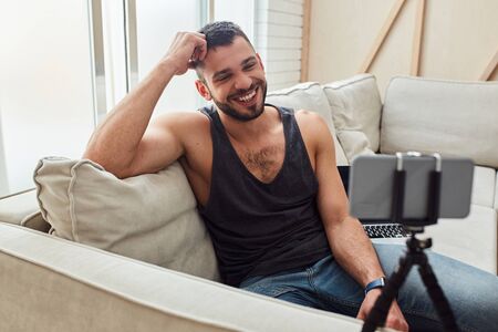 Cheerful gentleman talking with friend through video callの写真素材