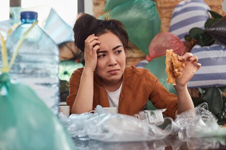 Young female with disheveled hair is turning her flat into trash heap