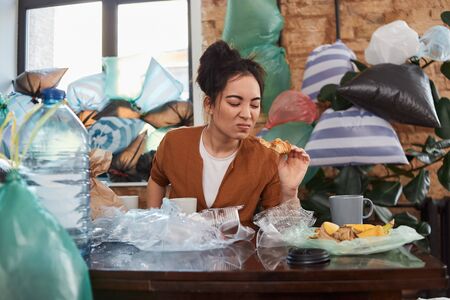 Unkempt female looking on a piece of rotten food with disgustの写真素材