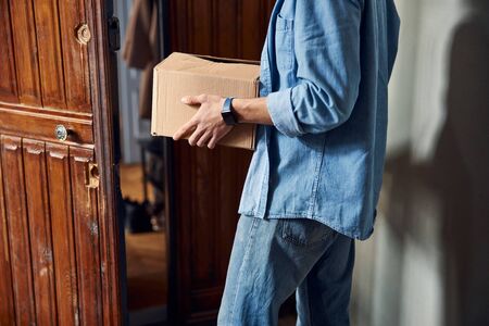 Young man holding cardboard box delivered to the doorの写真素材