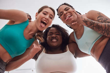 Cheerful multiracial friends making funny faces, showing tongues and goat gestureの写真素材