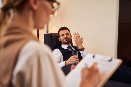Dissatisfied elegant man talking with woman with folderの写真素材