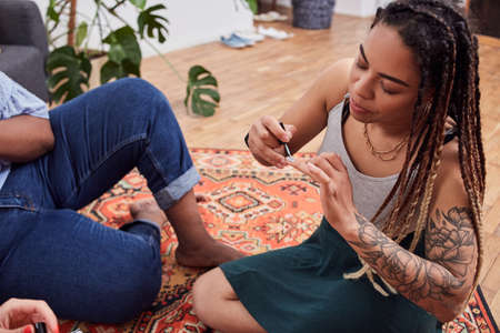 Afro american woman painting her nails on floor