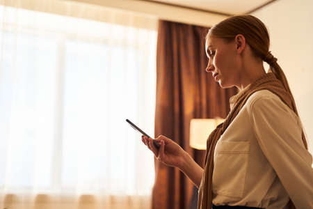 Serious young woman messaging on smartphone indoorsの写真素材