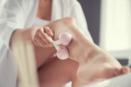 Low angle cropped head close up of woman calfs while she is massaging them in bathroom