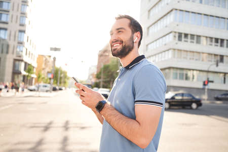 Smiling young man listening to music in city centreの写真素材